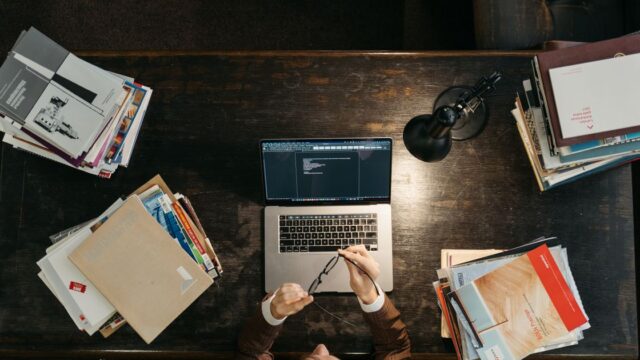 独学でITの資格取得を目指す人が教科書とパソコンで勉強している様子