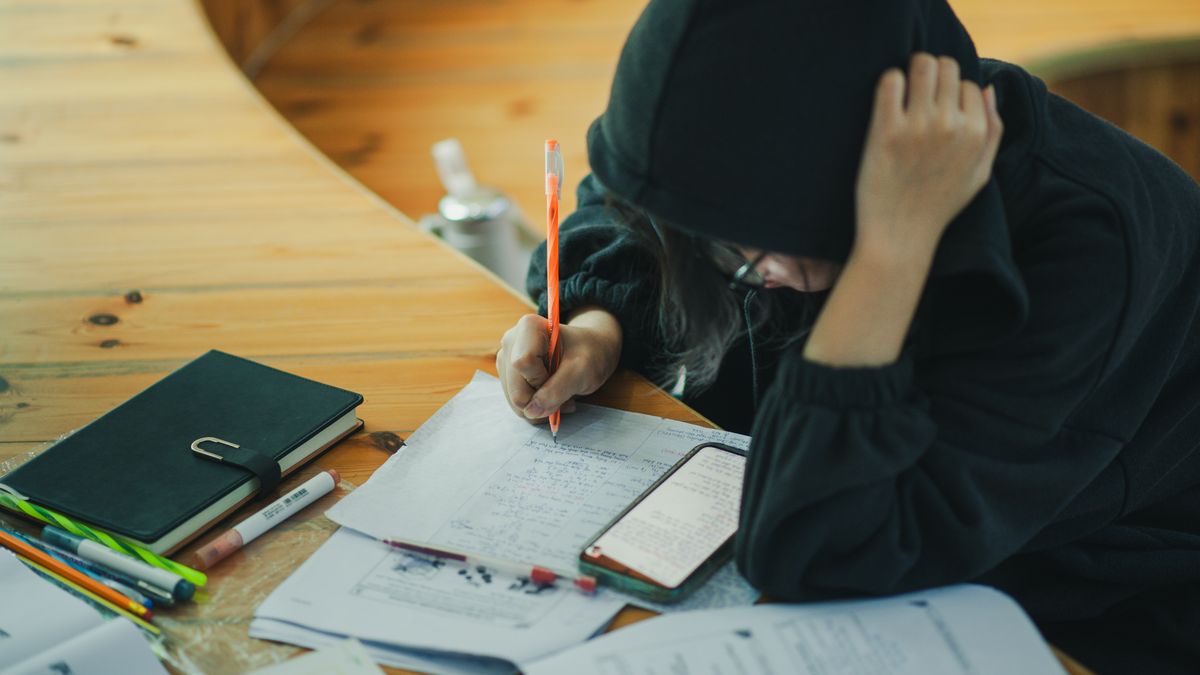 Japanese high school student studying at desk in the evening with notebook