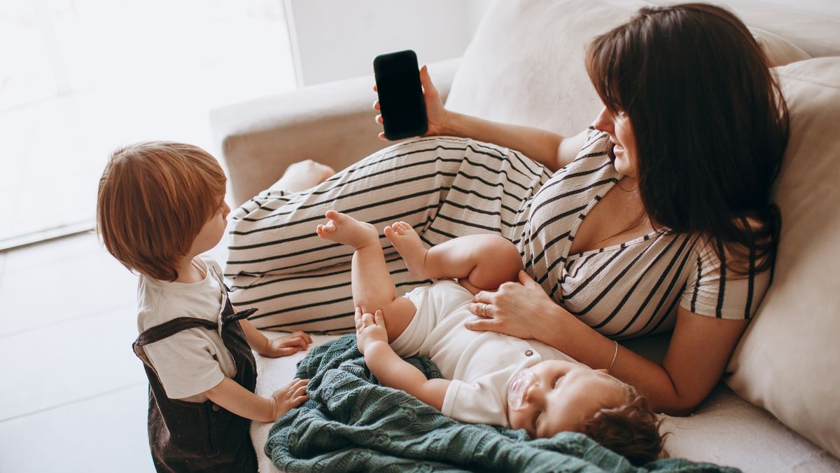 woman studying smartphone living room while baby sleeps