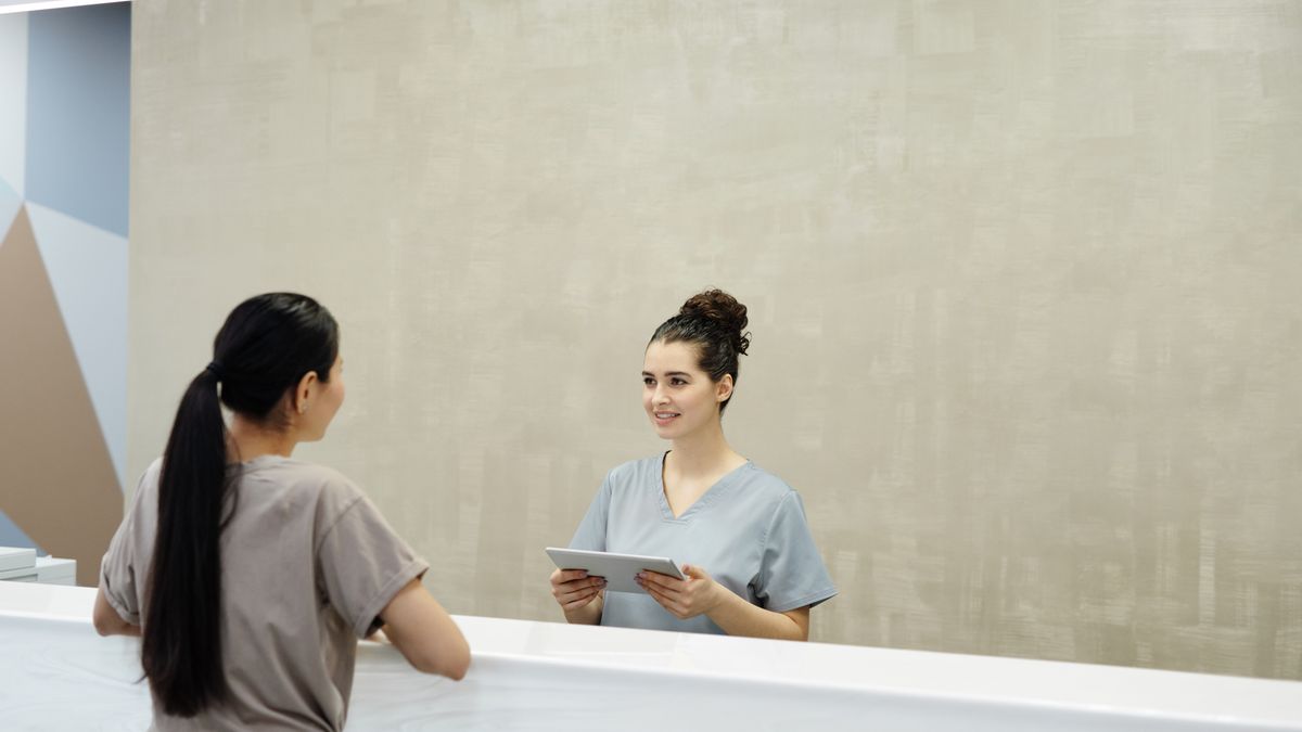 smiling woman working at a medical clinic reception desk