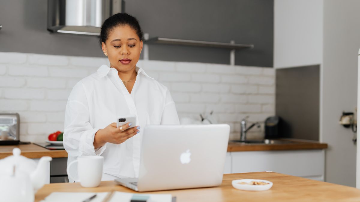 woman frowning while reading a smartphone email reply at a kitchen table
