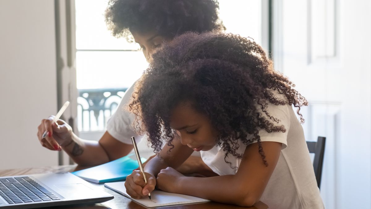 japanese mother studying at desk at home with child nearby