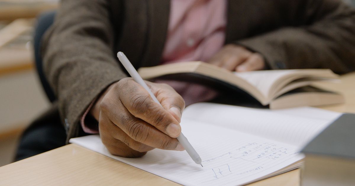 man studying with notebook, textbook at night desk