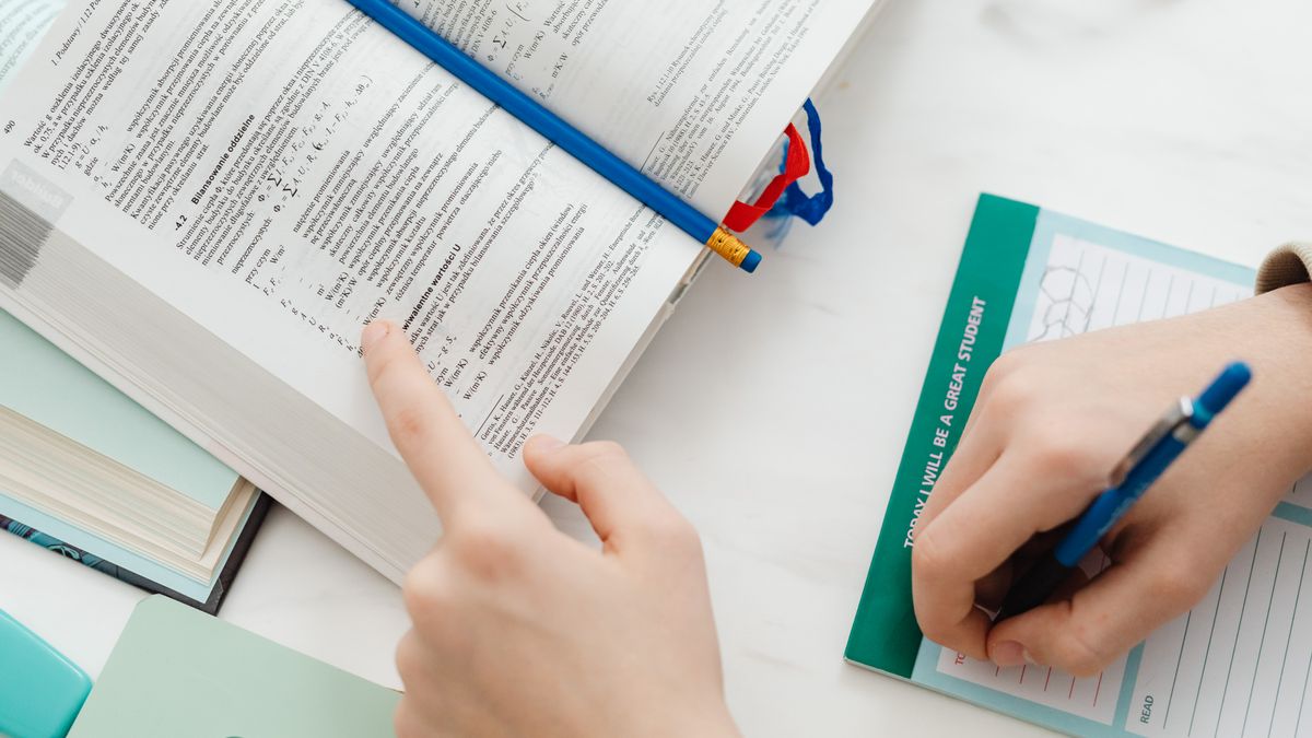 person studying mechanical engineering textbook at desk with notes