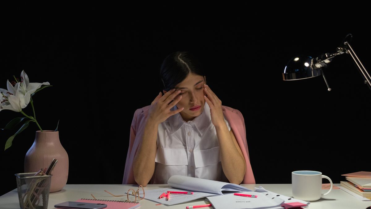tired businesswoman studying with notebook at night by desk lamp