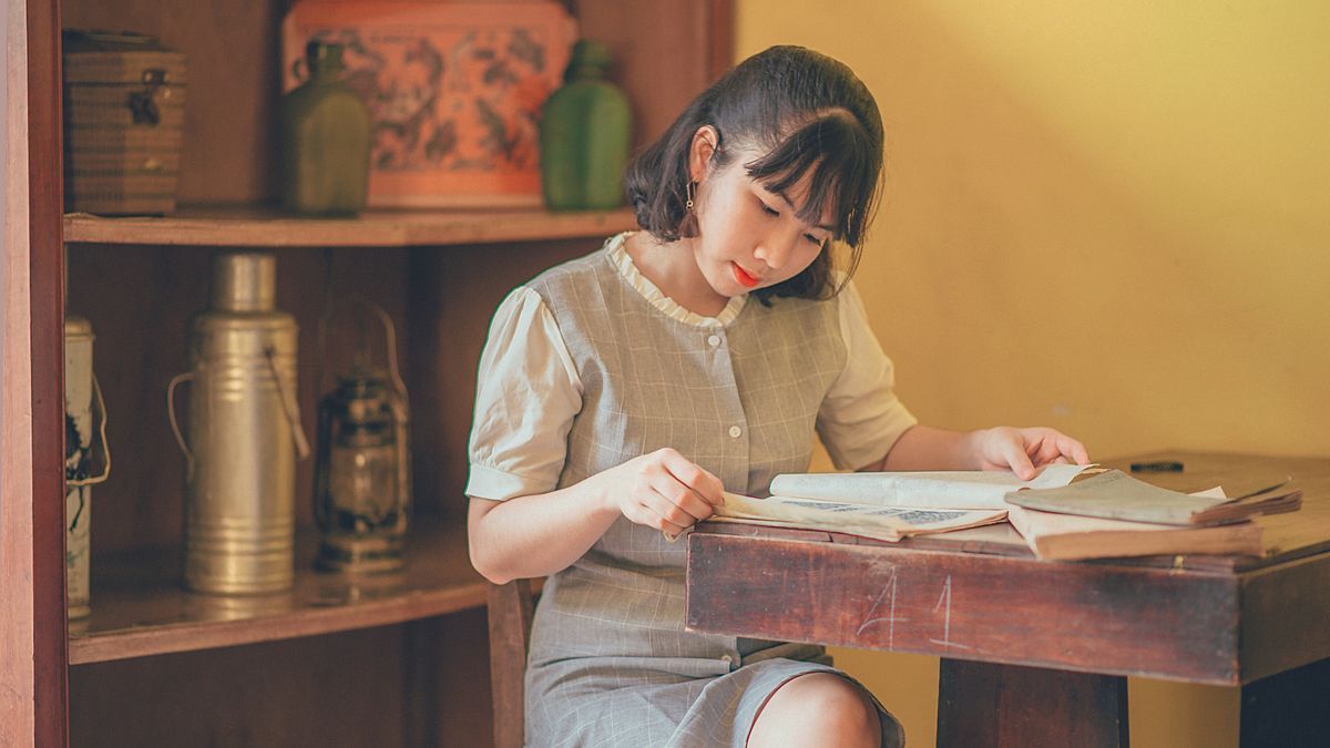 woman studying textbook at home desk