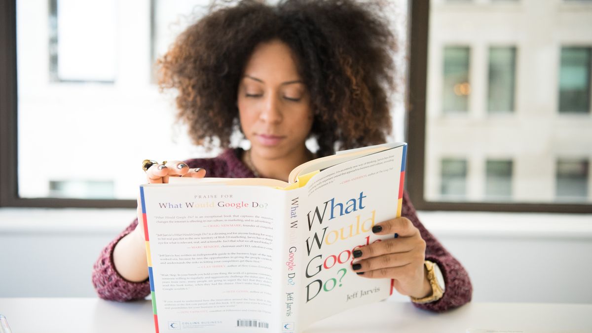 woman reading business book at desk