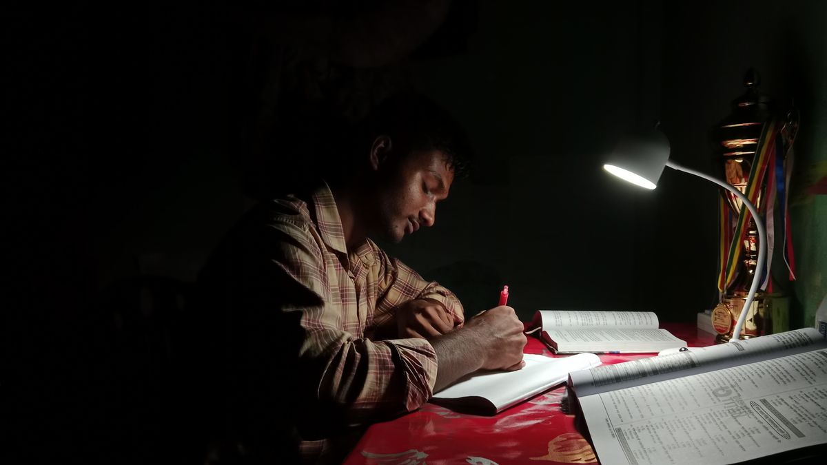man studying notebook desk lamp evening
