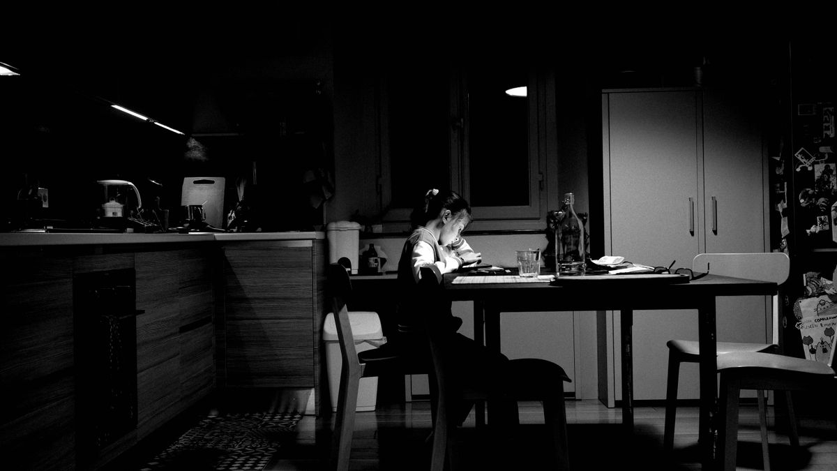 woman studying textbook kitchen table night