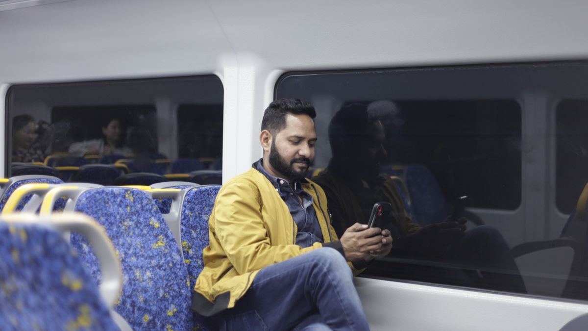 commuter reading smartphone train window