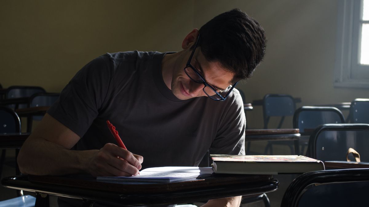 man studying textbook notebook desk evening