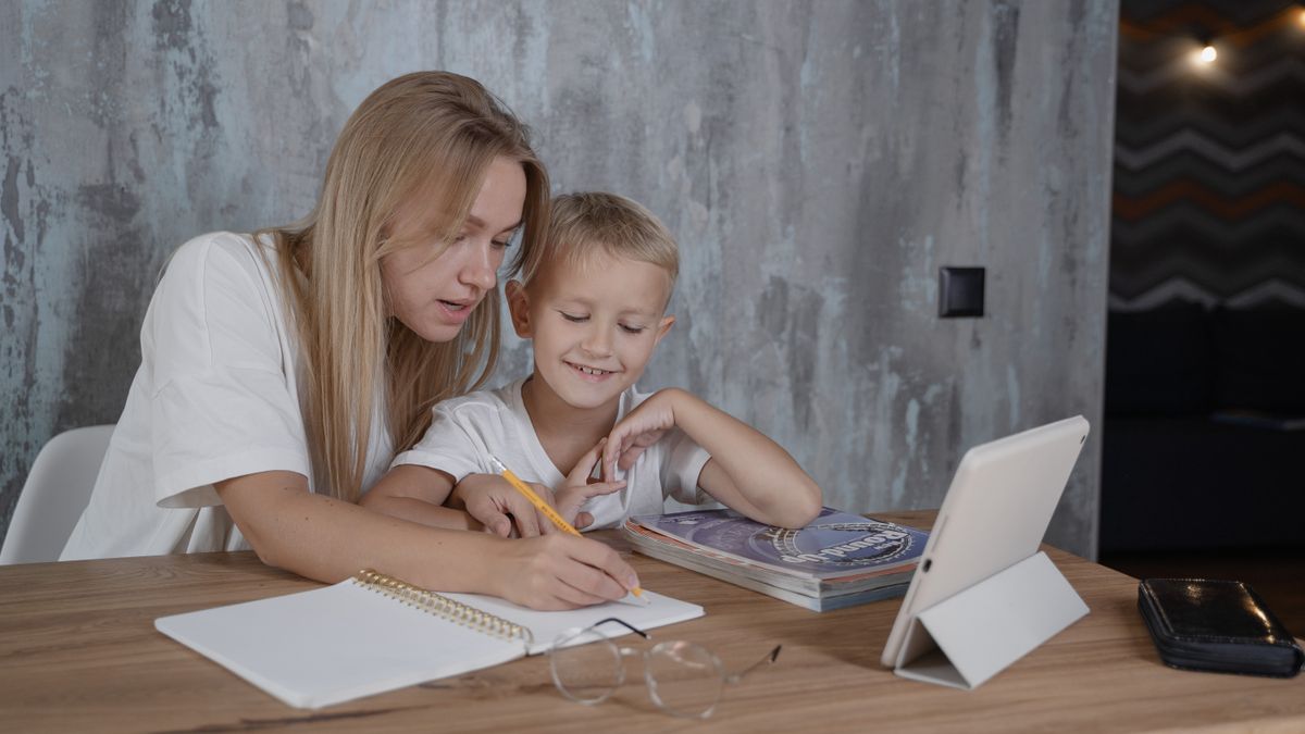 mother studying at home while child plays nearby