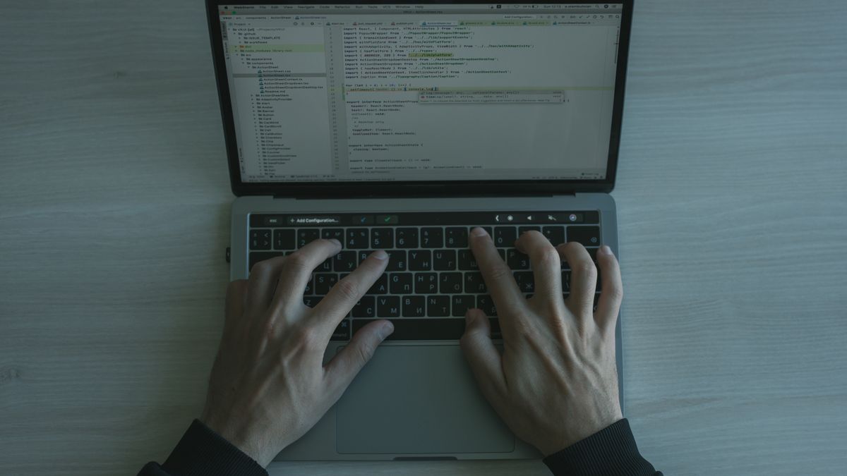 person typing laptop keyboard focused programming