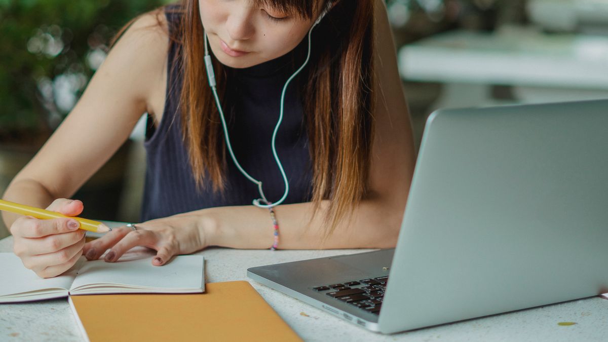 デスクでノートパソコンとノートを使って学習する女性