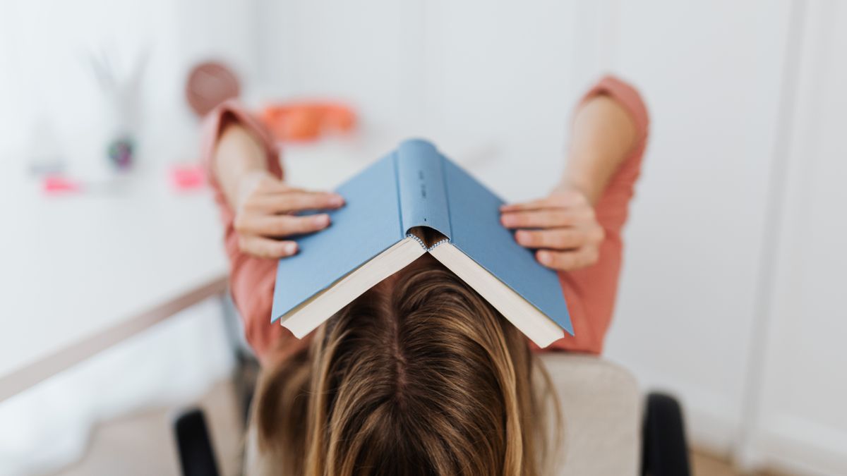 frustrated person studying textbook at desk