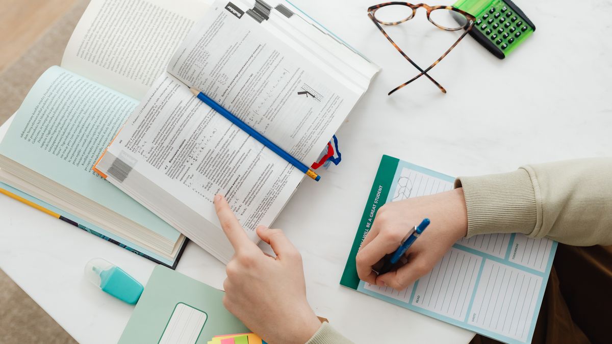 student studying accounting textbook with calculator at desk