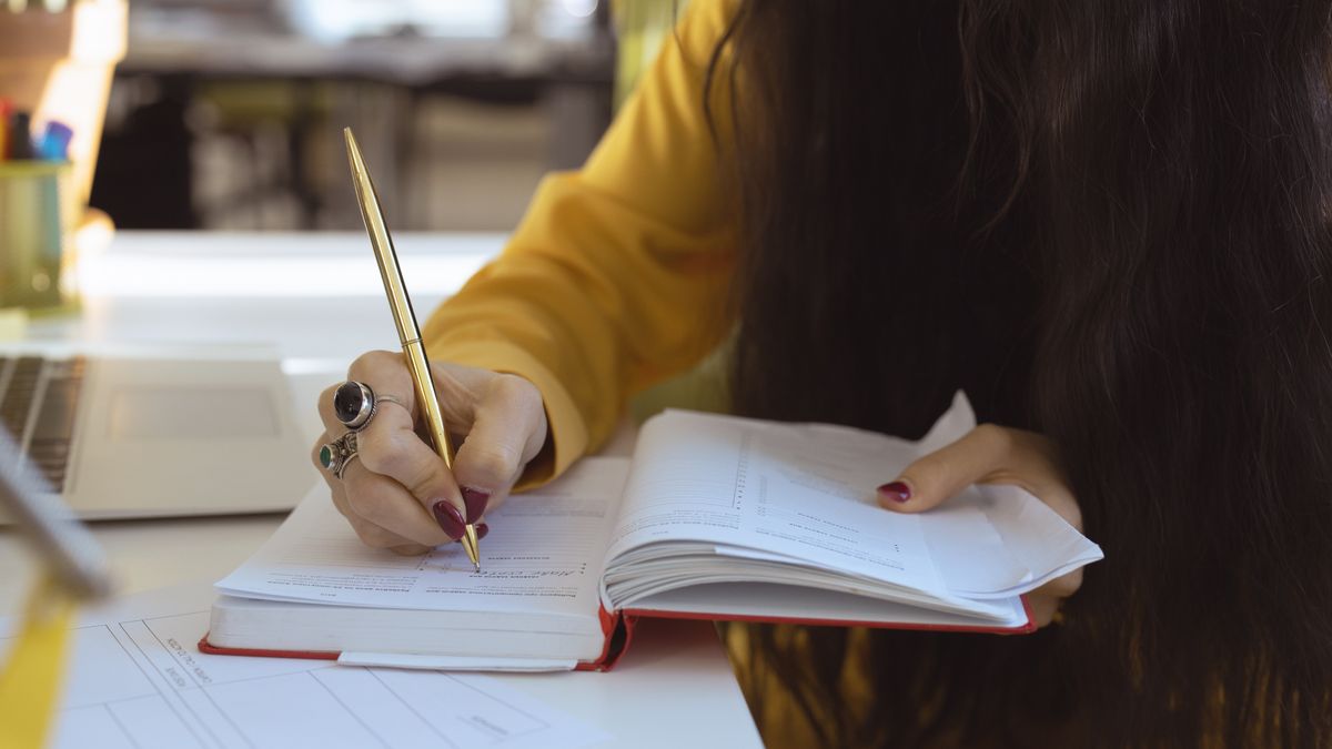 woman studying nail textbook at desk with notebook