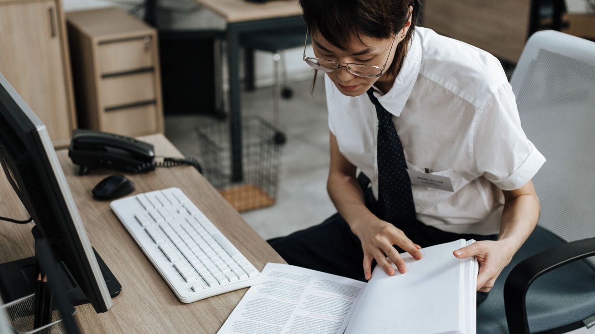 office worker reading certification guidebook desk