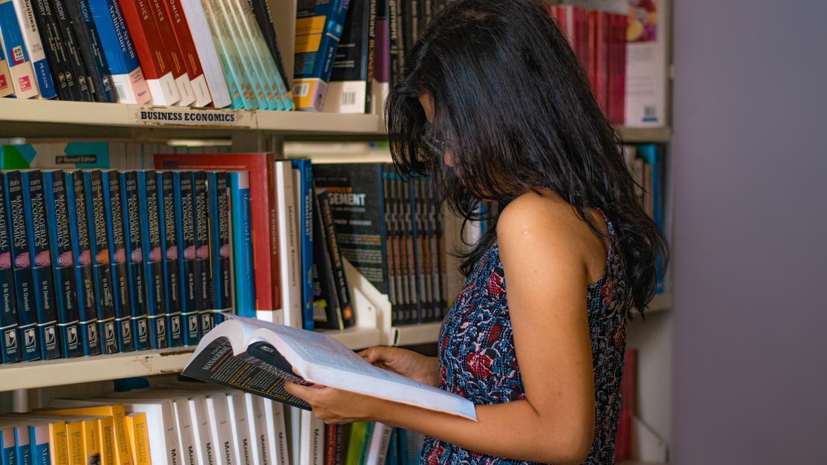 person comparing textbooks bookstore shelf