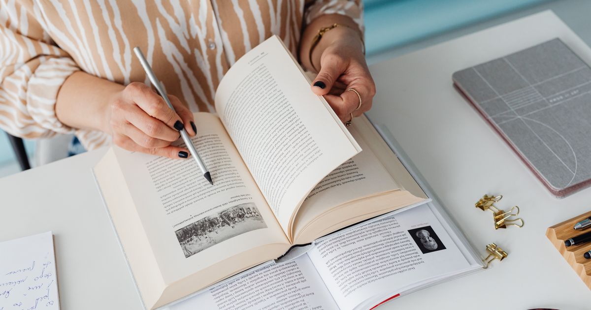 person studying textbook desk notes