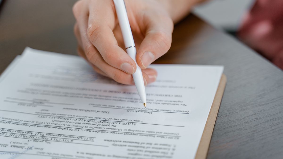 person filling exam application document desk