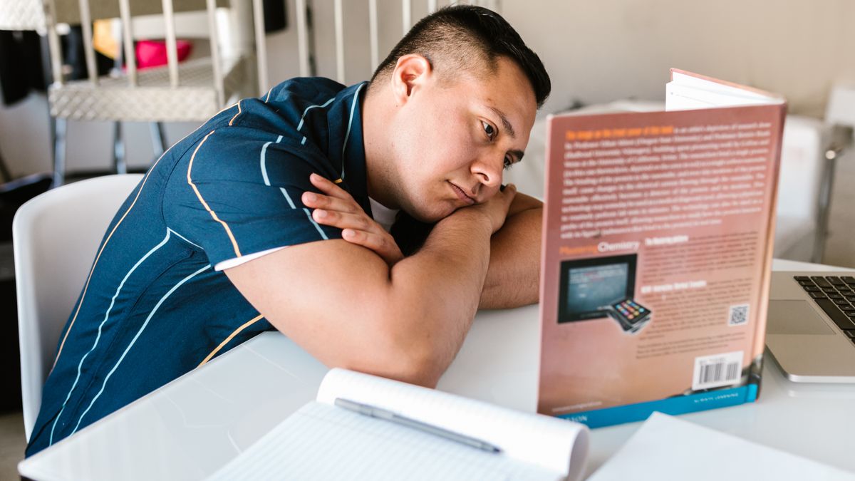 electrical engineer studying exam textbook at desk