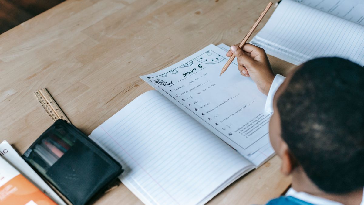 person studying textbook with notebook at desk