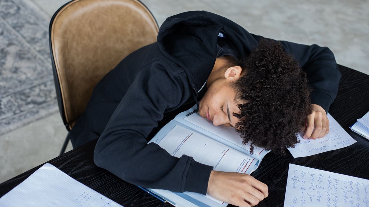 person studying for exam with textbooks at desk