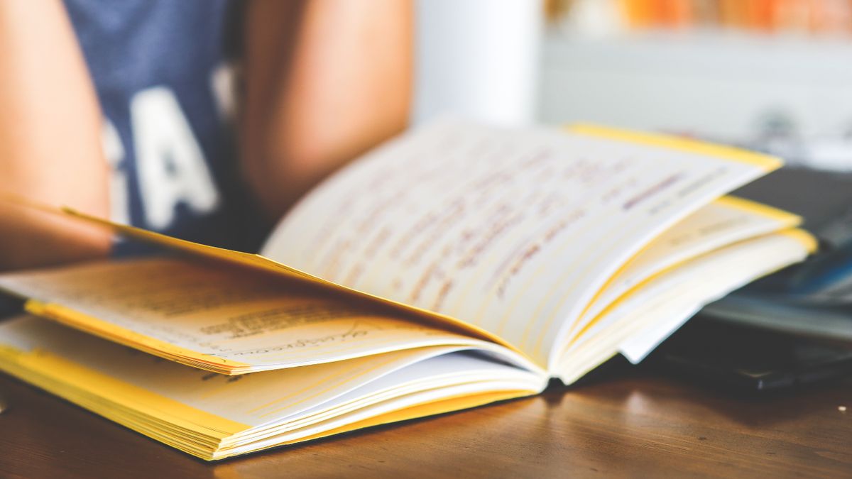 person studying textbook at desk with notes