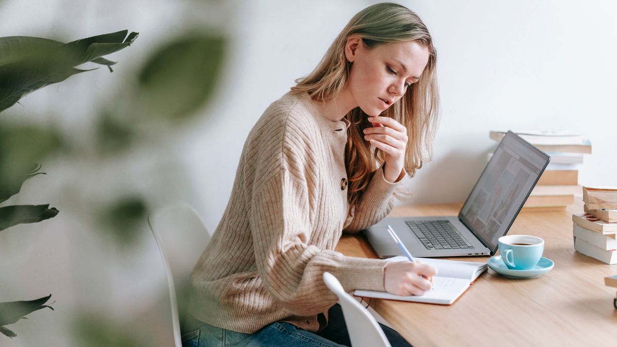 woman studying at home desk in the evening with notebook