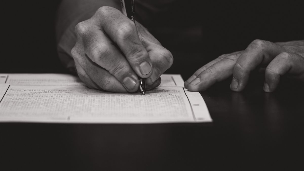 person filling out exam application form at desk