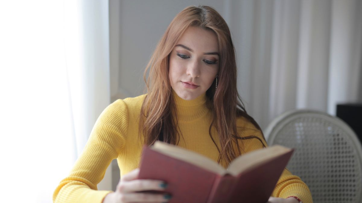 woman studying textbook at home desk