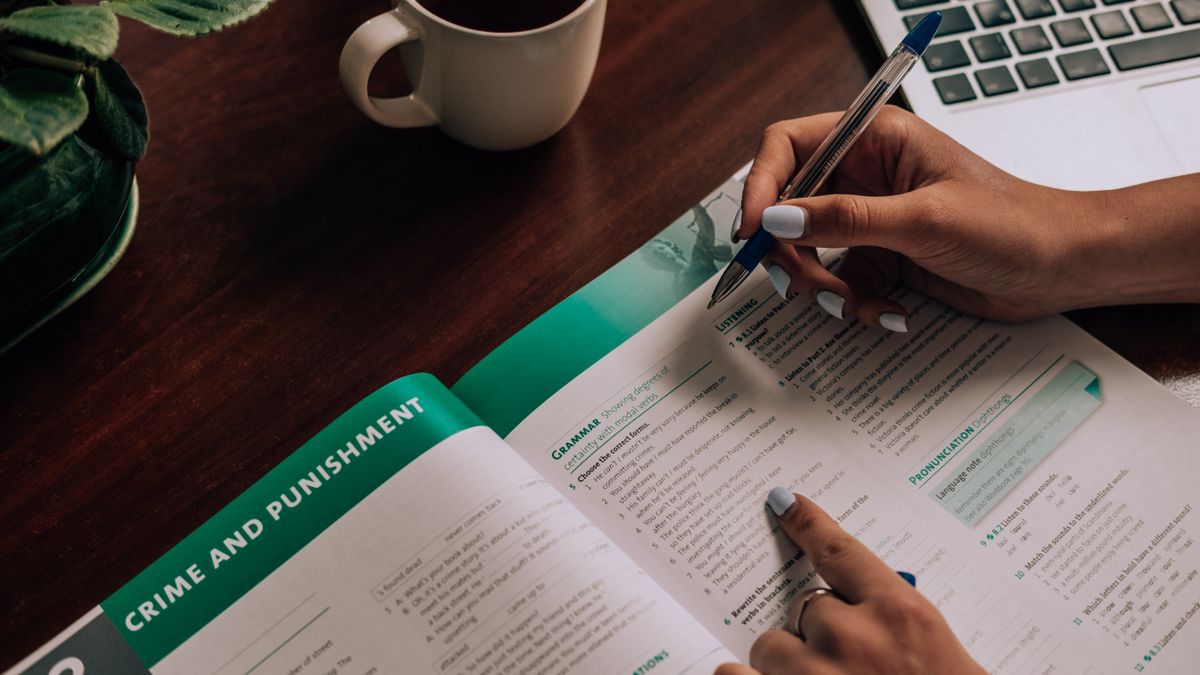 person studying textbook notes desk