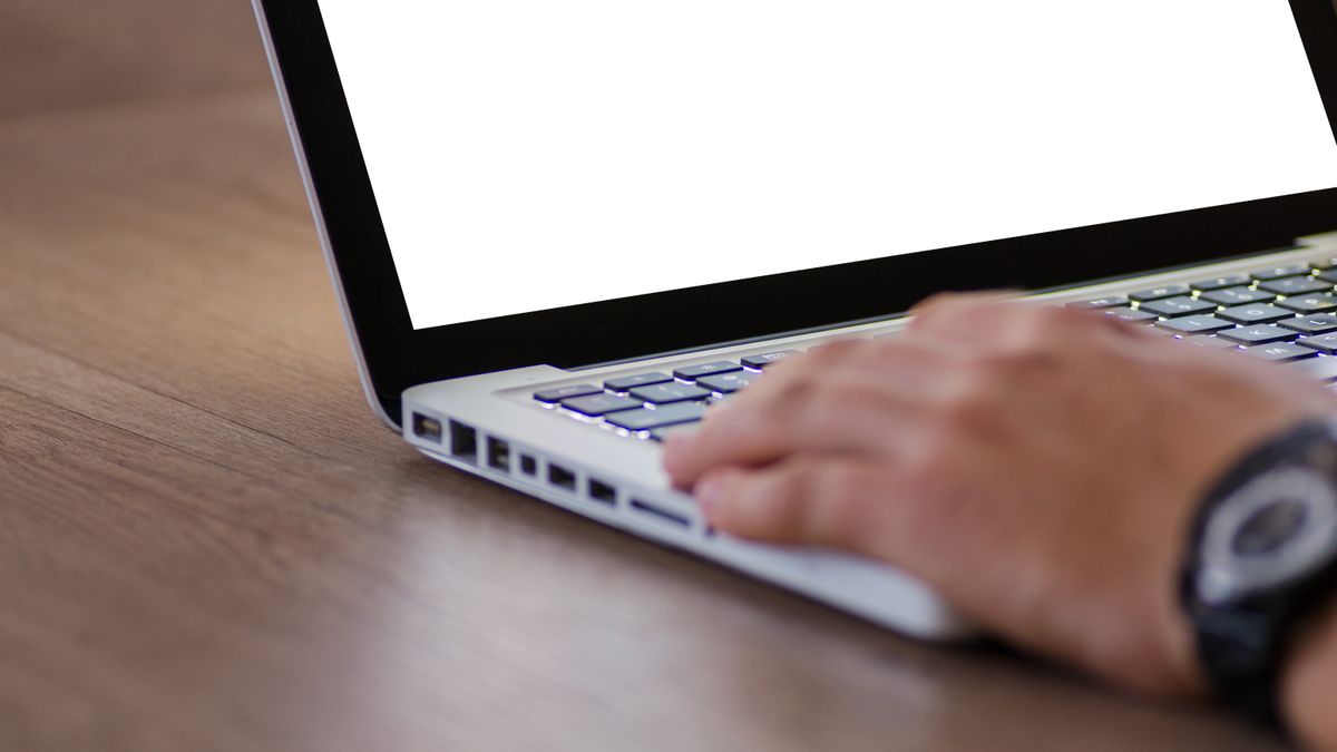 person typing on laptop keyboard in office