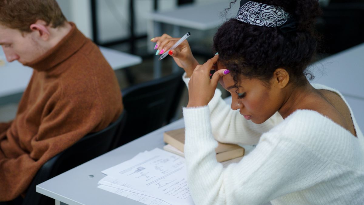 person solving exam questions at desk with pencil