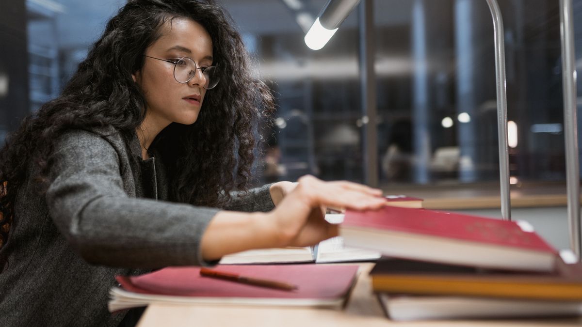 woman studying with textbook at night desk