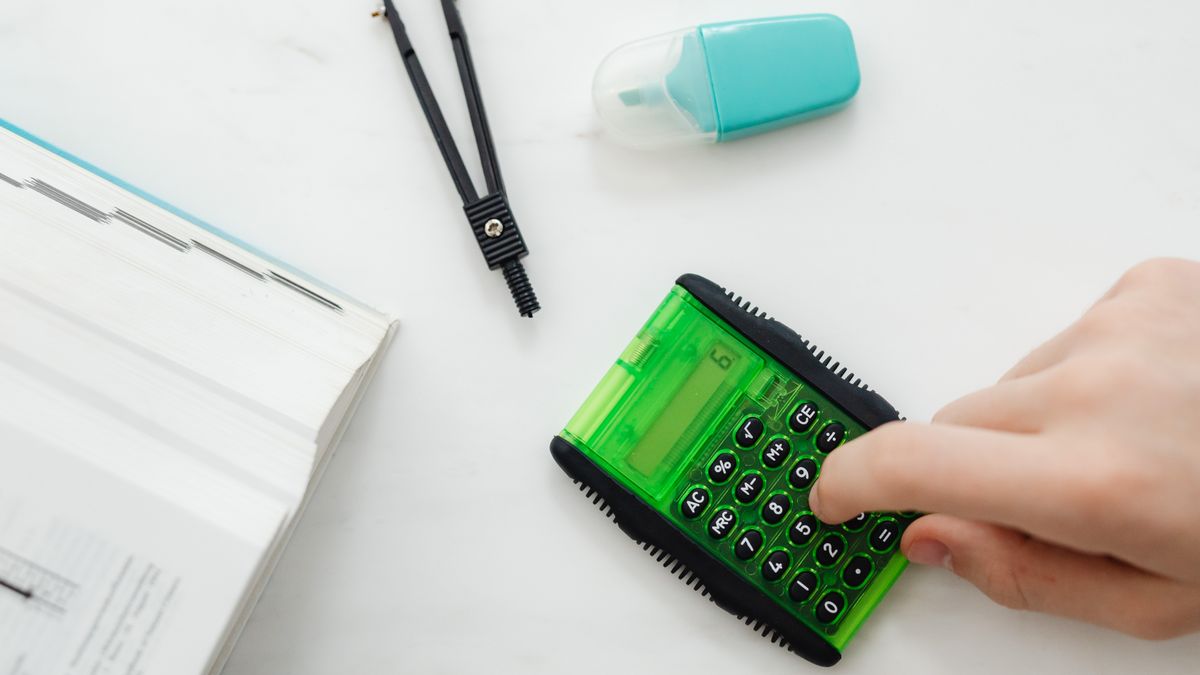 person studying finance textbook with calculator at desk