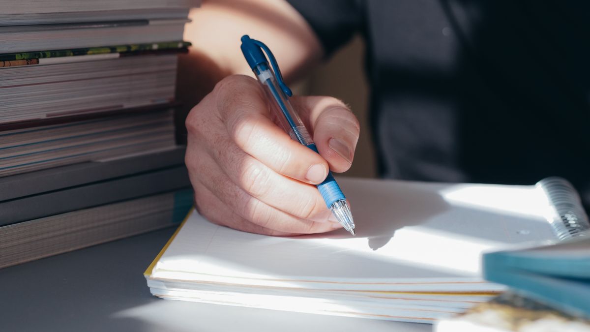 person studying exam book at desk night