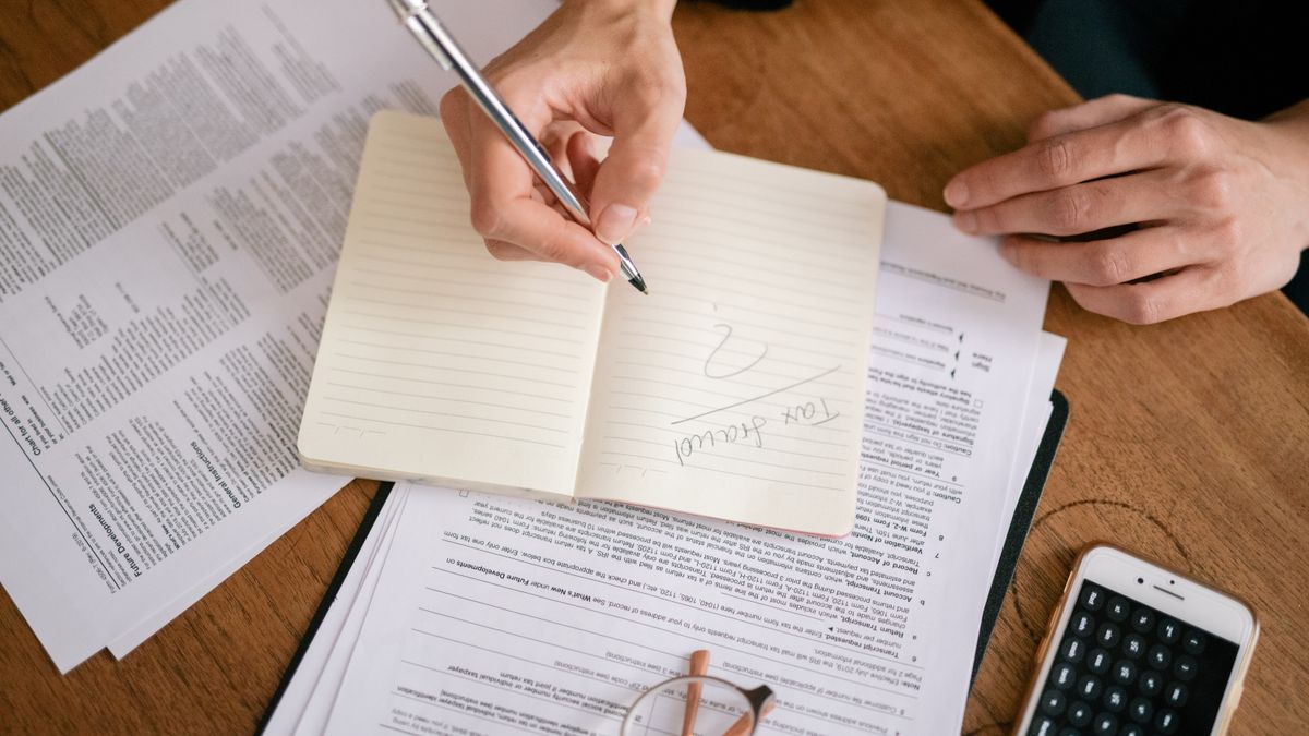 person writing calculations notebook calculator
