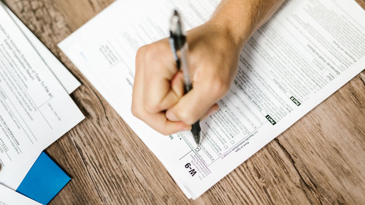 person writing resume at desk with pen