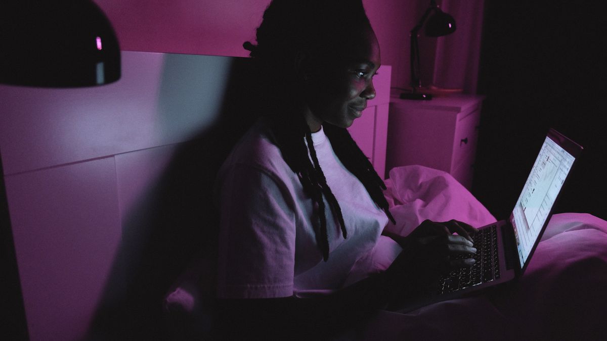 person reading online comments on laptop at night