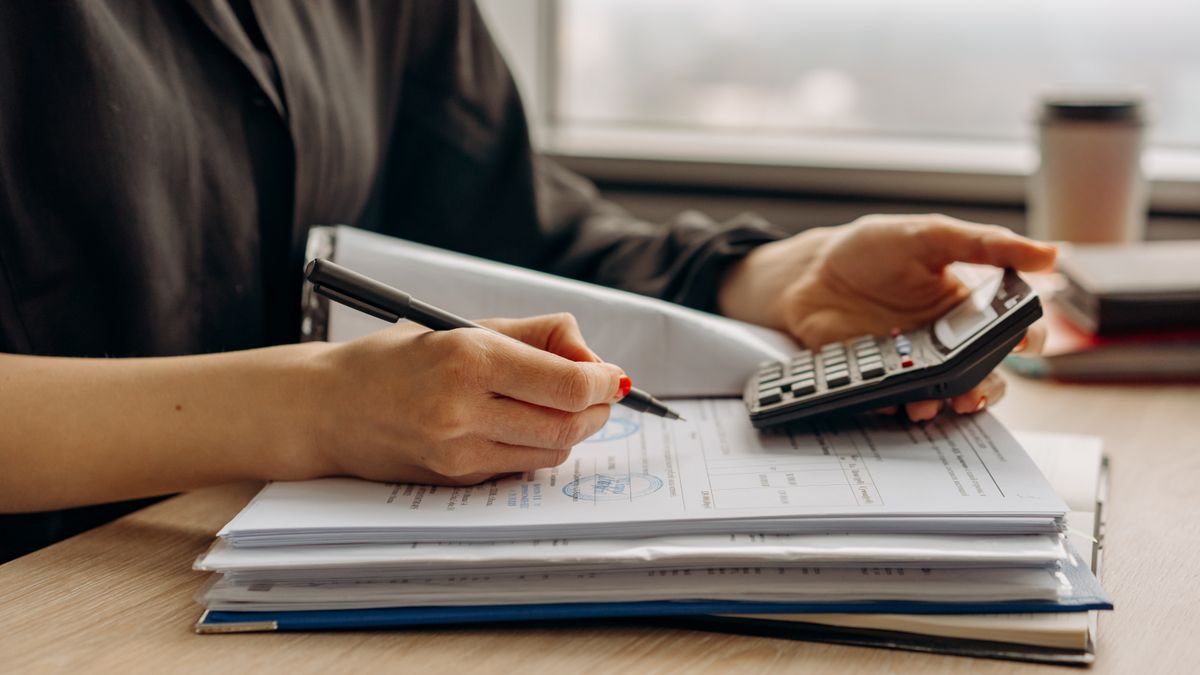 person calculating salary with calculator at desk