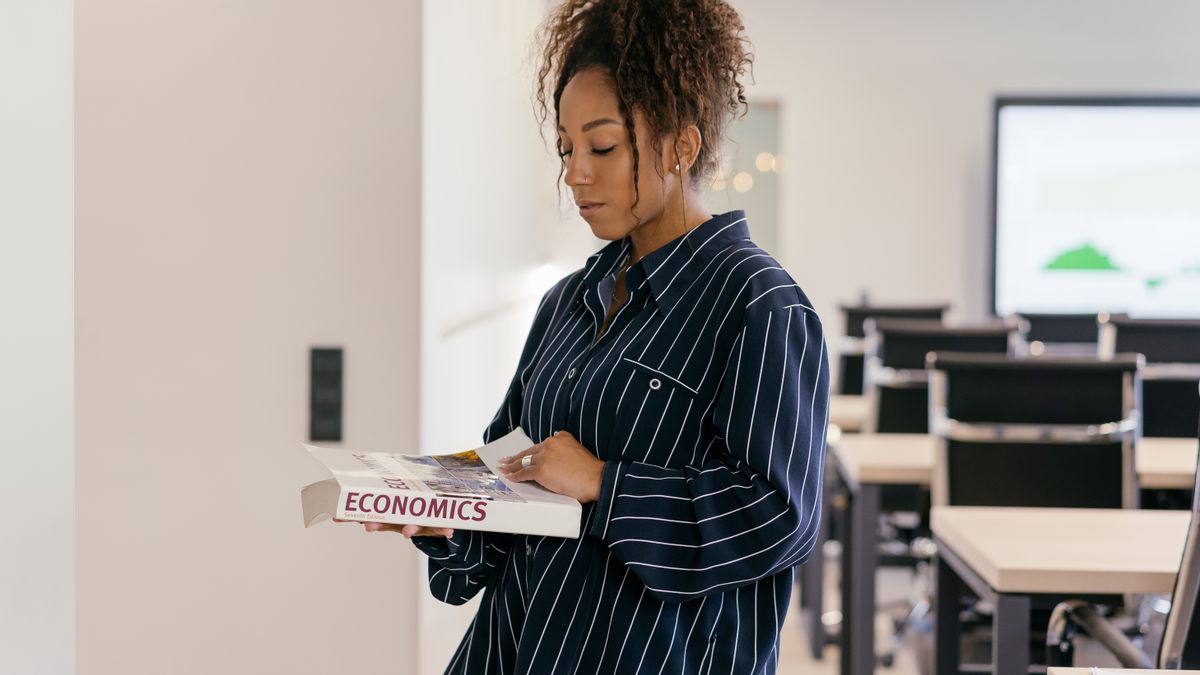 young woman studying textbook at desk